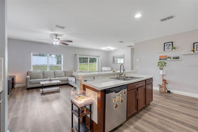 kitchen featuring light hardwood / wood-style floors, an island with sink, ceiling fan, stainless steel dishwasher, and sink