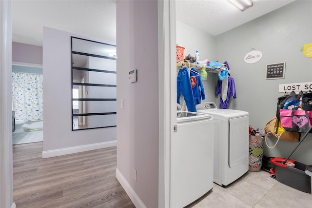 washroom featuring independent washer and dryer, a textured ceiling, and light tile patterned flooring