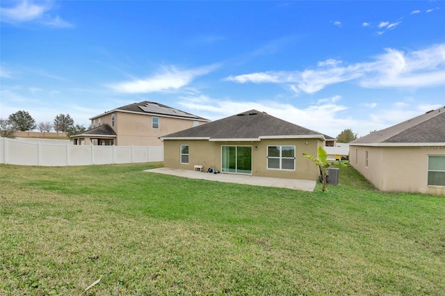 rear view of property featuring cooling unit, a yard, and a patio