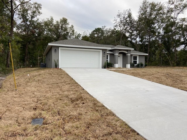 ranch-style home with a front yard, central air condition unit, and a garage