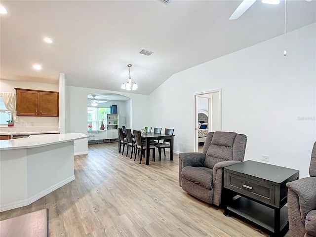 interior space featuring lofted ceiling, light wood-type flooring, ceiling fan with notable chandelier, and pendant lighting