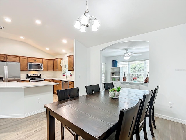 dining area with ceiling fan with notable chandelier, sink, lofted ceiling, and light wood-type flooring