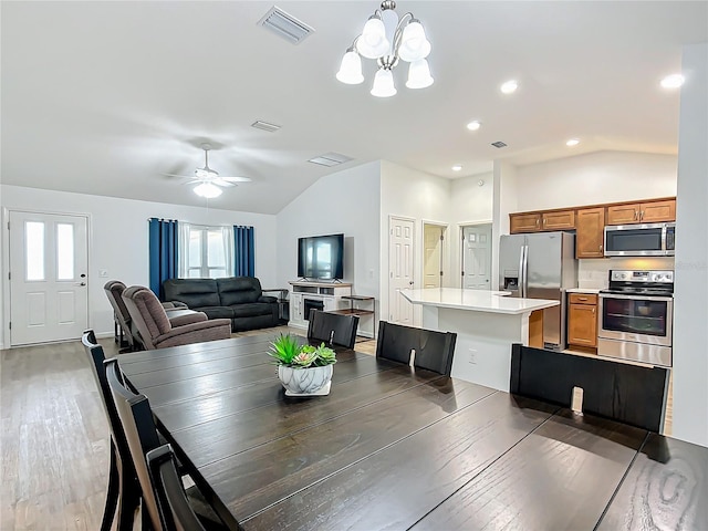 dining space with ceiling fan with notable chandelier, dark hardwood / wood-style floors, and lofted ceiling