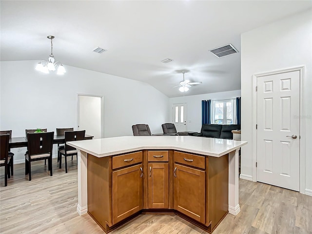 kitchen featuring light hardwood / wood-style floors, lofted ceiling, a kitchen island, pendant lighting, and ceiling fan with notable chandelier