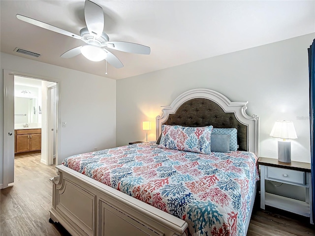 bedroom featuring ceiling fan, ensuite bathroom, hardwood / wood-style flooring, and sink