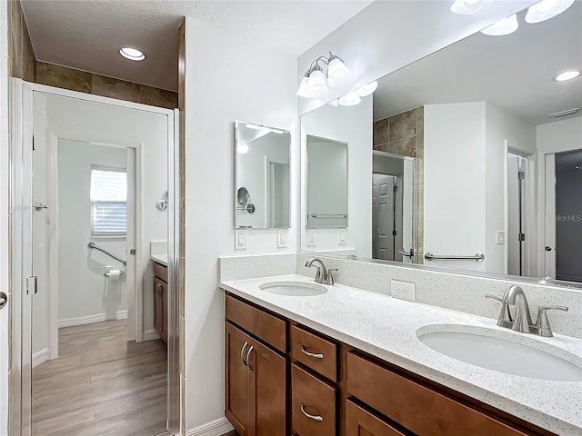 bathroom featuring hardwood / wood-style flooring, a shower with door, and vanity