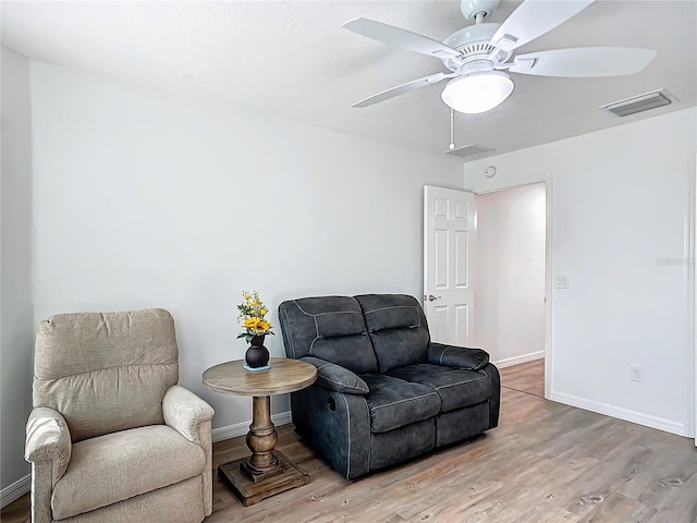 sitting room with ceiling fan and wood-type flooring