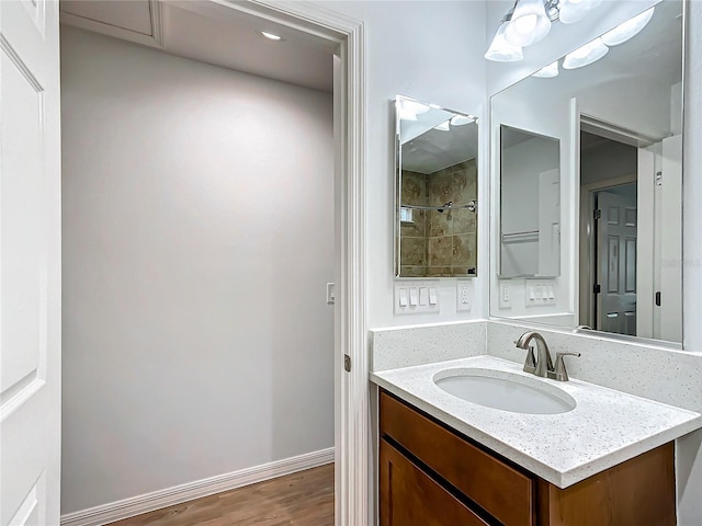 bathroom featuring vanity, wood-type flooring, and a tile shower