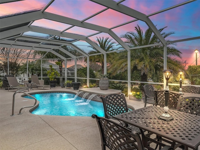 pool at dusk featuring pool water feature, a patio, and glass enclosure