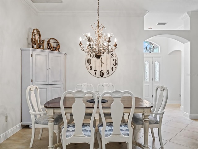 dining area with light tile patterned flooring, ornamental molding, and an inviting chandelier