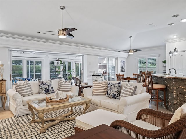 living room featuring crown molding, sink, and ceiling fan