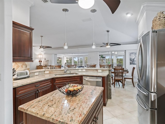 kitchen with pendant lighting, sink, a kitchen island with sink, stainless steel appliances, and light stone countertops