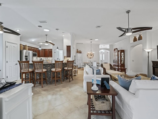 living room with crown molding, ceiling fan with notable chandelier, and a wall unit AC