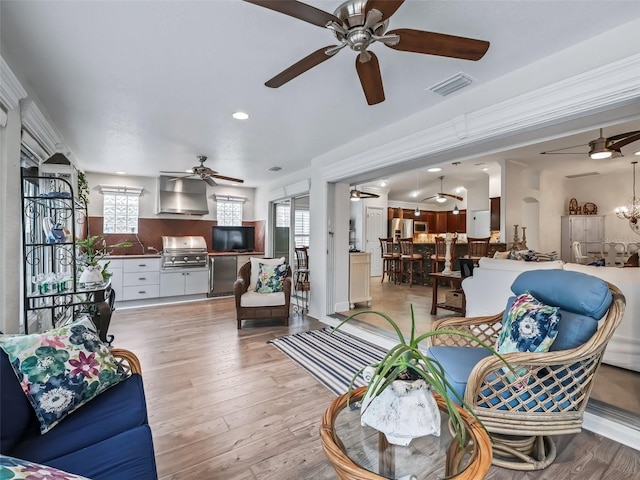 living room with ceiling fan with notable chandelier and light wood-type flooring