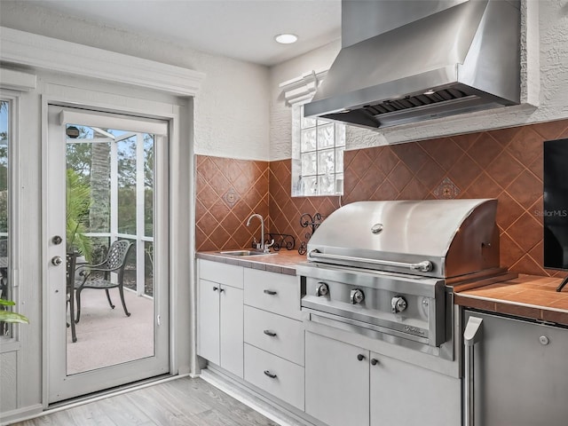 kitchen featuring white cabinetry, sink, light hardwood / wood-style flooring, and exhaust hood