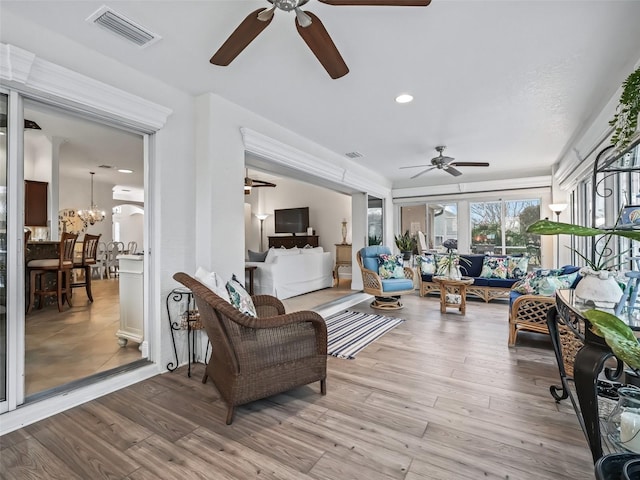 sunroom / solarium featuring ceiling fan with notable chandelier