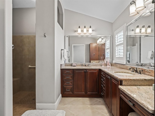 bathroom with vaulted ceiling, vanity, tile patterned flooring, and a tile shower