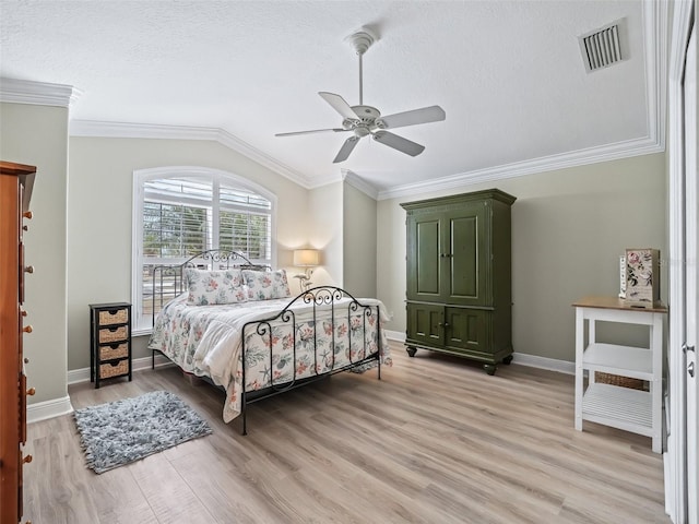 bedroom featuring lofted ceiling, a textured ceiling, light wood-type flooring, ornamental molding, and ceiling fan