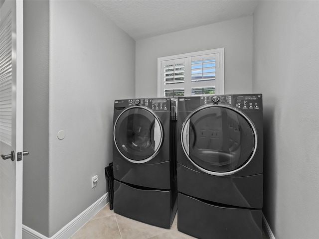 washroom featuring light tile patterned floors, washing machine and dryer, and a textured ceiling