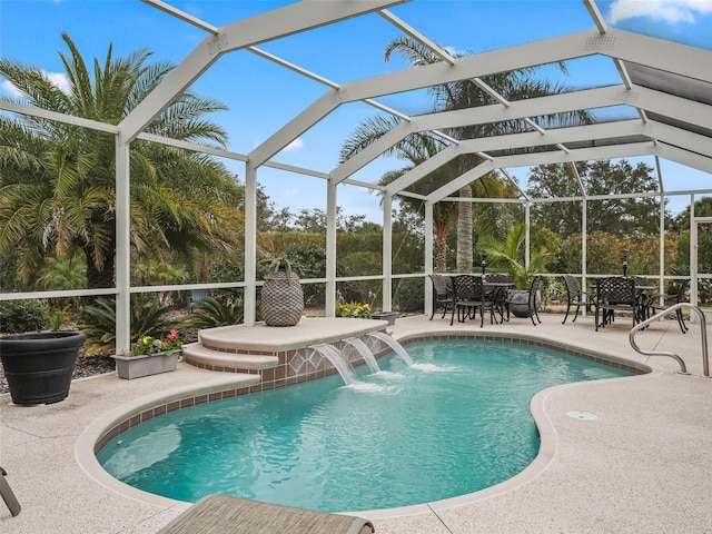 view of pool with a patio, pool water feature, and glass enclosure