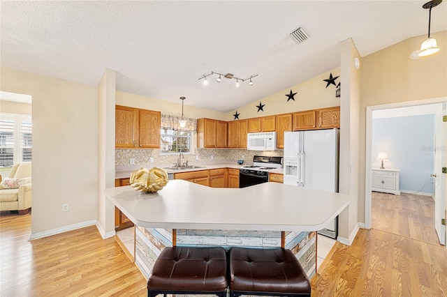 kitchen featuring hanging light fixtures, white appliances, vaulted ceiling, and sink