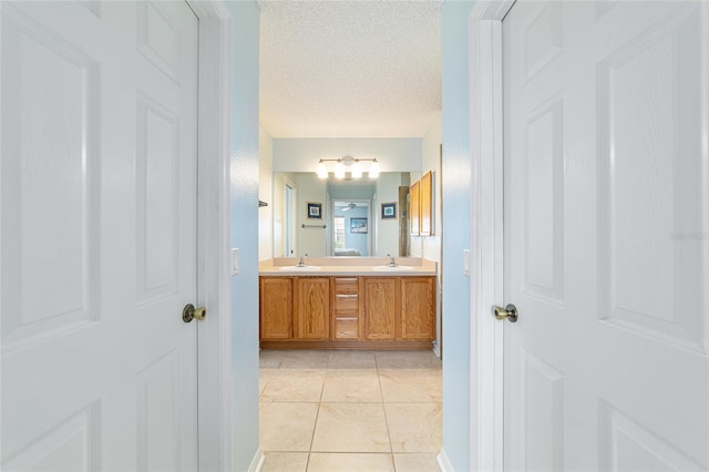 bathroom with tile patterned flooring, vanity, and a textured ceiling