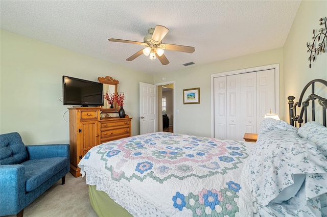 bedroom with ceiling fan, light colored carpet, a closet, and a textured ceiling