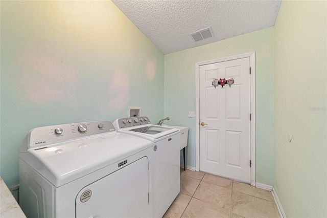 laundry area featuring separate washer and dryer, sink, light tile patterned floors, and a textured ceiling