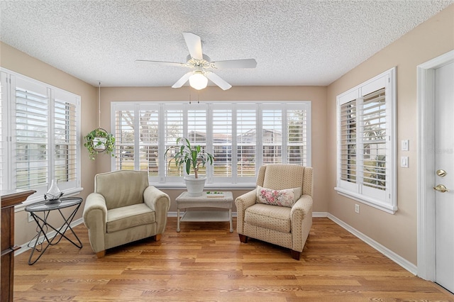 living area featuring ceiling fan, light hardwood / wood-style floors, and a textured ceiling