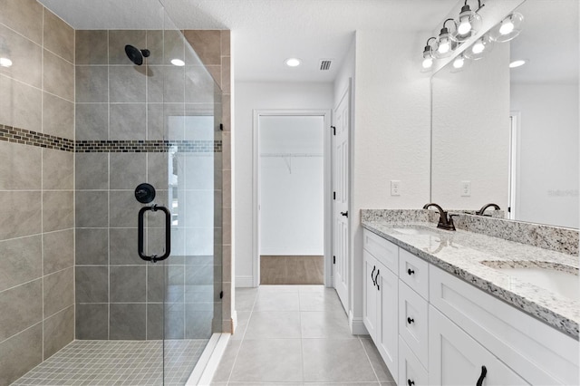 bathroom with an enclosed shower, vanity, and tile patterned flooring