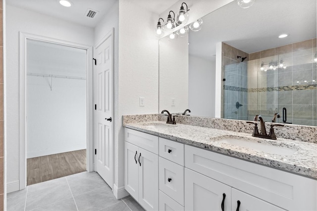 bathroom featuring a shower with shower door, vanity, and tile patterned flooring