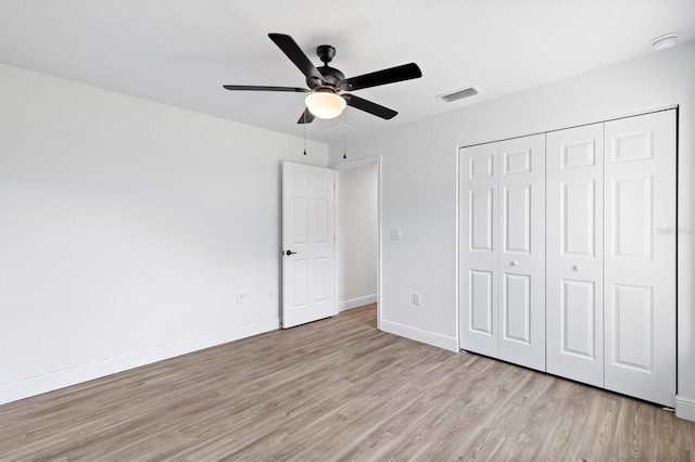 unfurnished bedroom featuring ceiling fan, a closet, and light wood-type flooring