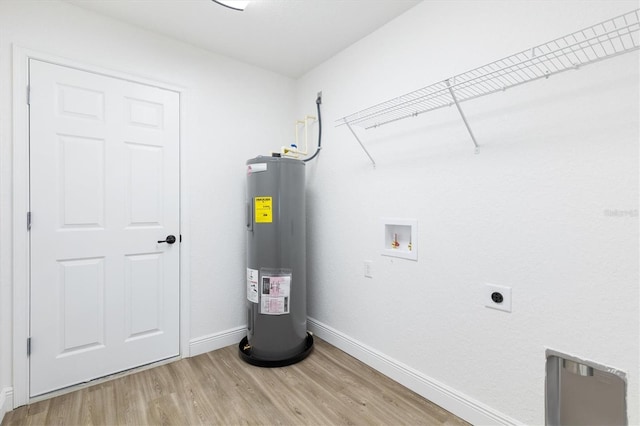 washroom with water heater, hardwood / wood-style flooring, hookup for a washing machine, and hookup for an electric dryer