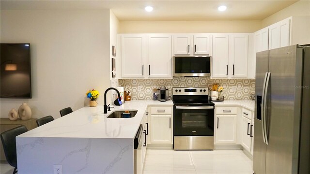 kitchen featuring kitchen peninsula, appliances with stainless steel finishes, backsplash, a kitchen breakfast bar, and sink