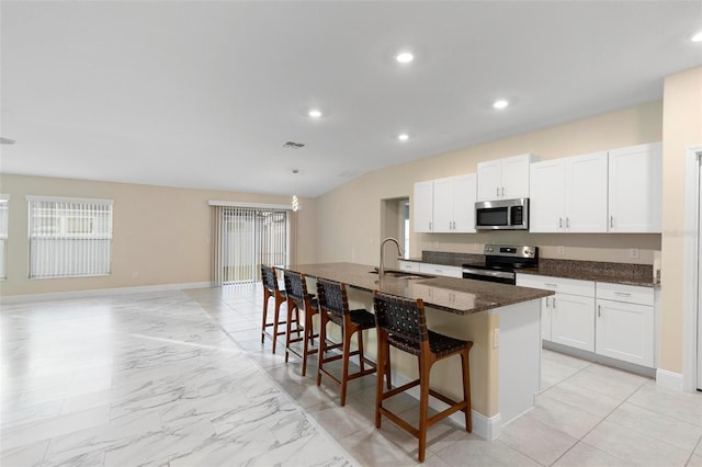 kitchen featuring an island with sink, white cabinetry, sink, a kitchen bar, and stainless steel appliances