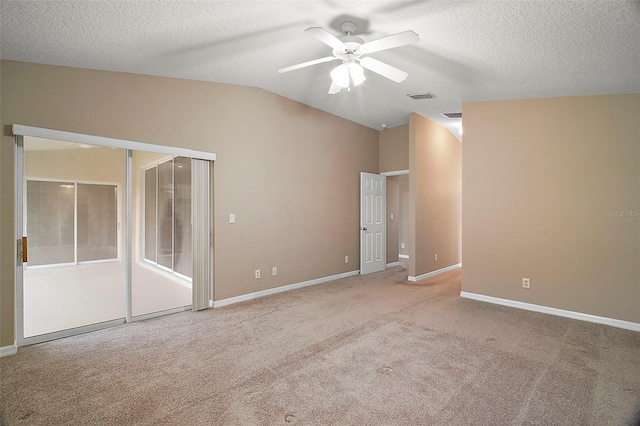 unfurnished bedroom with lofted ceiling, light carpet, a textured ceiling, a closet, and ceiling fan