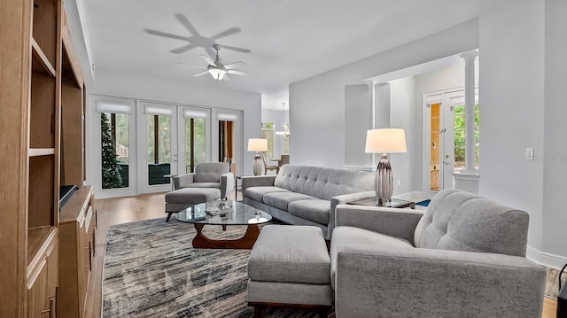 living room featuring ceiling fan, wood-type flooring, and decorative columns