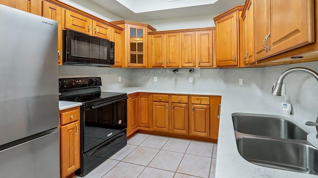 kitchen with light tile patterned floors, sink, decorative backsplash, and black appliances