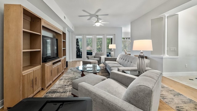 living room featuring decorative columns, built in features, ceiling fan, and light wood-type flooring