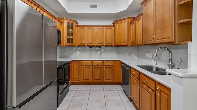 kitchen with black appliances, a raised ceiling, decorative backsplash, sink, and light tile patterned floors