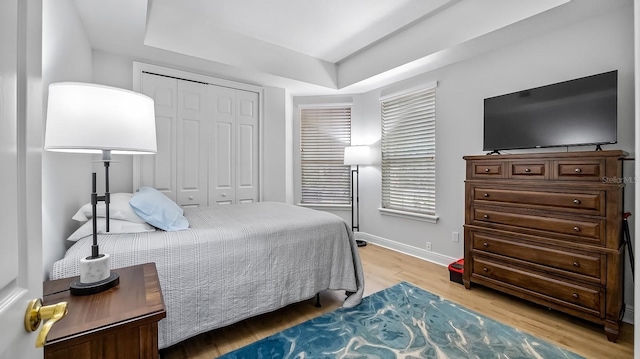 bedroom featuring a closet, a raised ceiling, and light hardwood / wood-style flooring