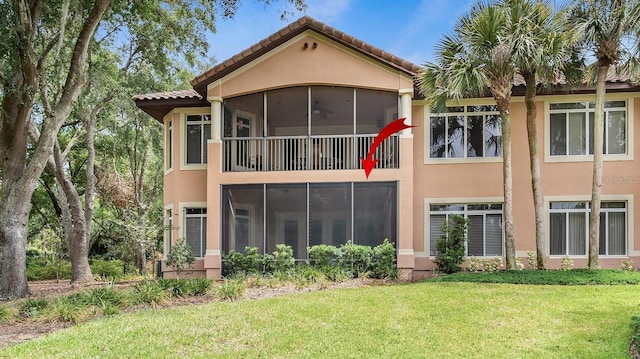 back of property with ceiling fan, a sunroom, and a yard