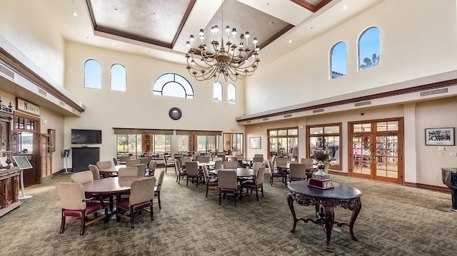 carpeted dining room with an inviting chandelier, a towering ceiling, and a raised ceiling