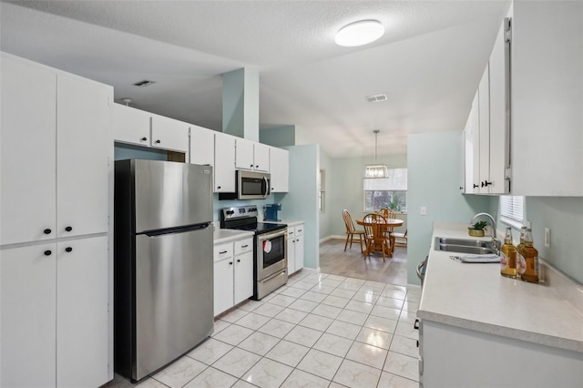 kitchen with appliances with stainless steel finishes, white cabinets, decorative light fixtures, and sink