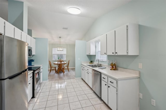 kitchen featuring lofted ceiling, pendant lighting, sink, stainless steel appliances, and white cabinets