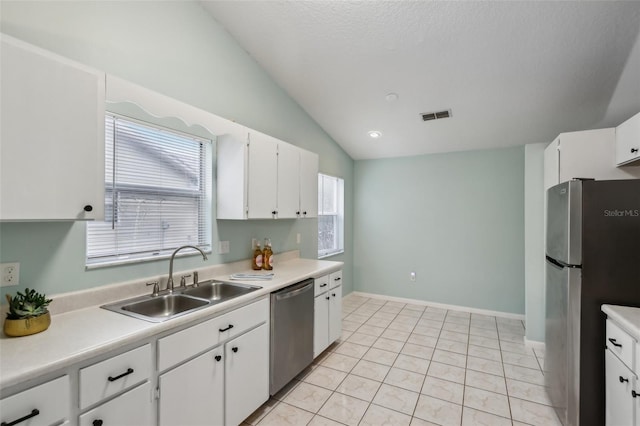 kitchen with light tile patterned floors, white cabinetry, stainless steel appliances, vaulted ceiling, and sink