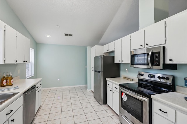 kitchen with white cabinets, stainless steel appliances, and vaulted ceiling