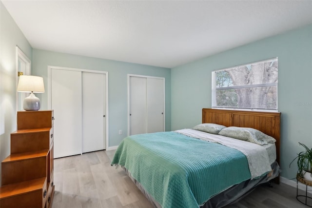 bedroom with light wood-type flooring and two closets