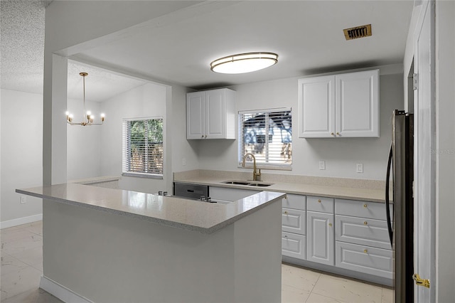 kitchen featuring white cabinets, sink, hanging light fixtures, black fridge, and kitchen peninsula