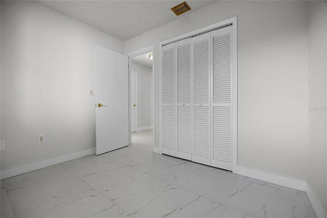 unfurnished bedroom featuring a textured ceiling and a closet